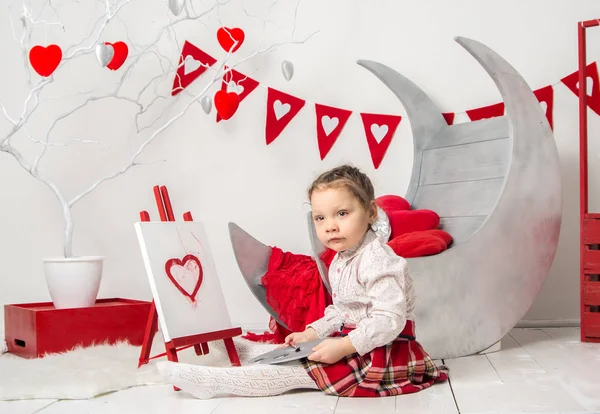portrait of a little girl draws in an interior Valentine's Day