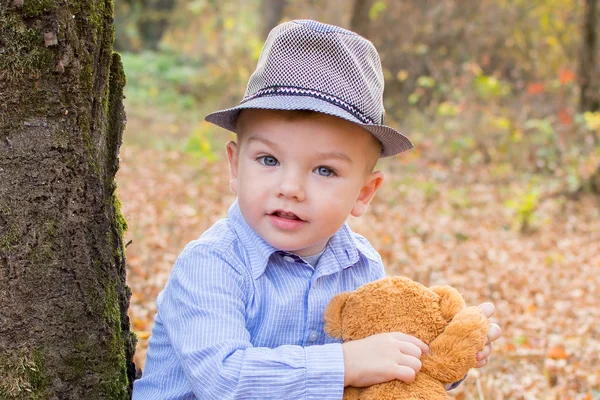 Menino em um chapéu na floresta de outono com um brinquedo em suas mãos — Fotografia de Stock