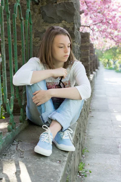 Menina pensativa e triste sentado perto da cerca — Fotografia de Stock