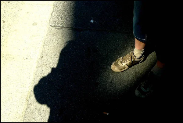 Man in sneakers standing in shadow outdoor