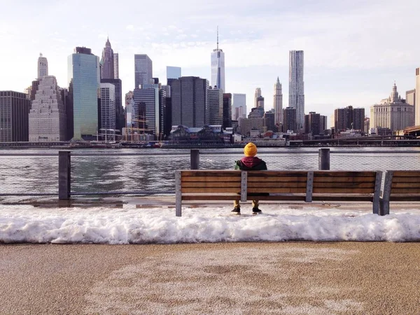 man sitting on the bench with City and  sea