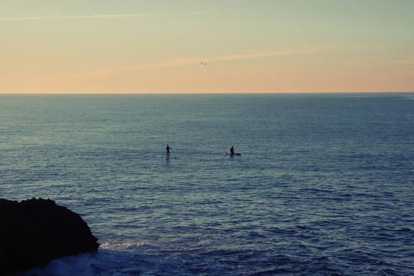 people Paddle In The Sea at the sunset
