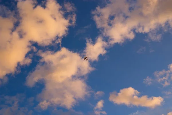 Airplane flying in sunset sky with clouds