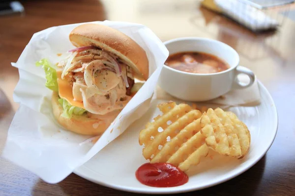 Lunch with seafood burger, potato crisps, coffee beverage on white plate