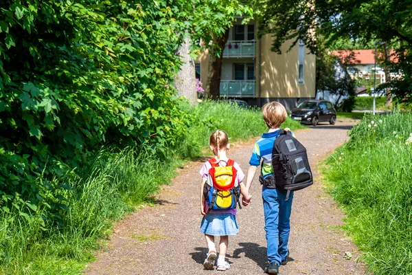 Chlapec a dívka chůzi držení rukou a na zádech batohy — Stock fotografie