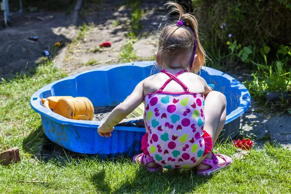 Söt liten flicka som leker i en sandlåda — Stockfoto
