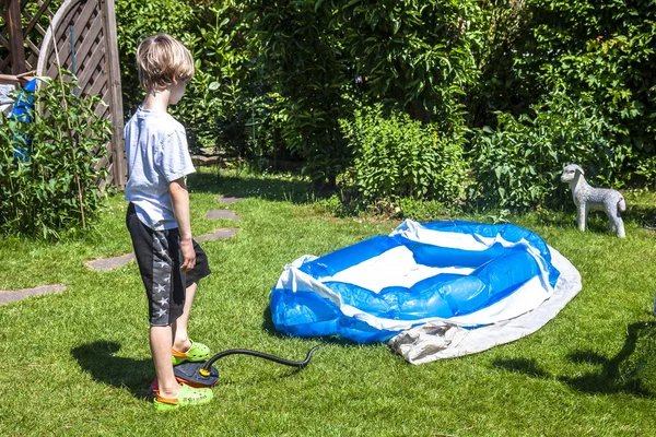 Lille pojken blåser upp uppblåsbara poolen — Stockfoto