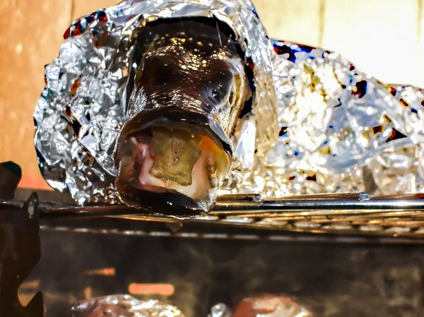 Fresh pike coiled in aluminium foil on barbecue — Stock Image Fresh pike coiled in aluminium foil on barbecue Royalty Free Stock Images