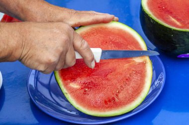 Adam kesme karpuz mavi plastik masa üzerinde.