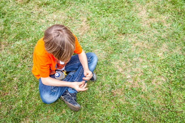 Pojedynczy znudzony teen chłopiec siedzi na trawie — Zdjęcie stockowe