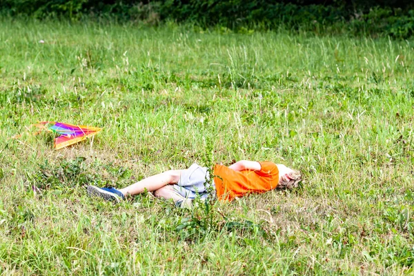 Boy totally exhausted after having fun flying a kite in summer