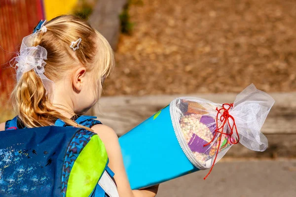 Niña parada frente al edificio de la escuela sosteniendo su cono de caramelo — Foto de Stock