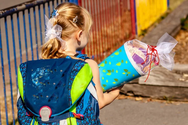 Niña parada frente al edificio de la escuela sosteniendo su cono de caramelo — Foto de Stock