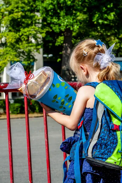 Niña parada frente al edificio de la escuela sosteniendo su cono de caramelo — Foto de Stock