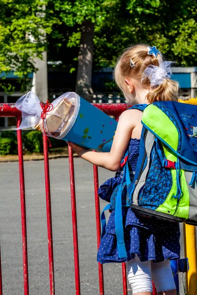 Niña parada frente al edificio de la escuela sosteniendo su cono de caramelo — Foto de Stock