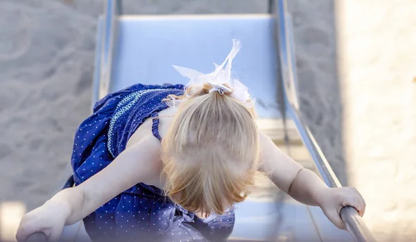 Petite fille mignonne s'amusant sur la glissière sur une aire de jeux en plein air en été — Photo
