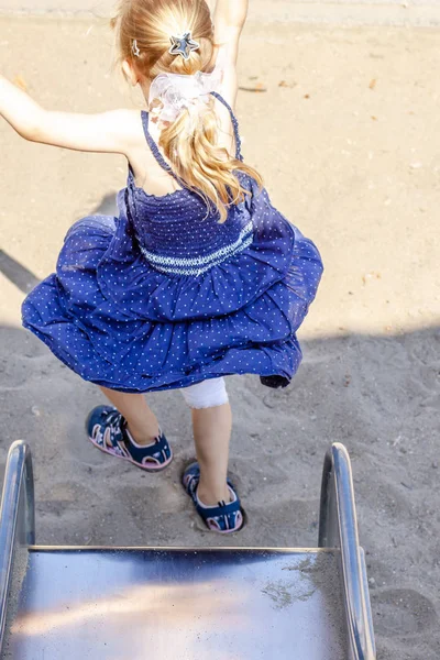 Linda niña divirtiéndose en diapositivas en un parque infantil al aire libre en verano — Foto de Stock
