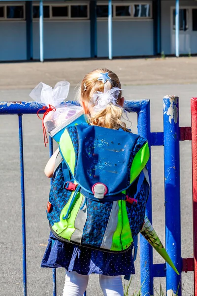 Niña parada frente al edificio de la escuela sosteniendo su cono de caramelo — Foto de Stock