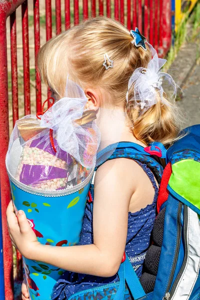 Niña parada frente al edificio de la escuela sosteniendo su cono de caramelo —  Fotos de Stock