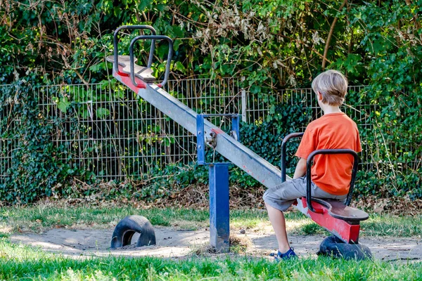 Jongen alleen spelen op de wip op de speelplaats — Stockfoto