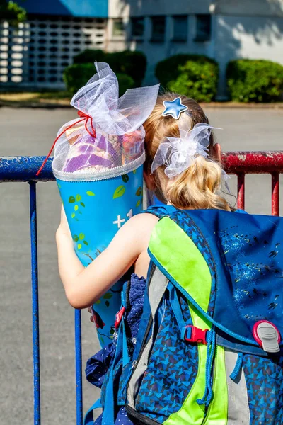 Ragazzina in piedi di fronte all'edificio scolastico con il cono di caramelle in mano — Foto Stock