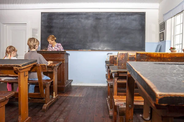 Концепция общеобразовательного начального образования с участием мальчика и девочки, слушающих учительницу — стоковое фото