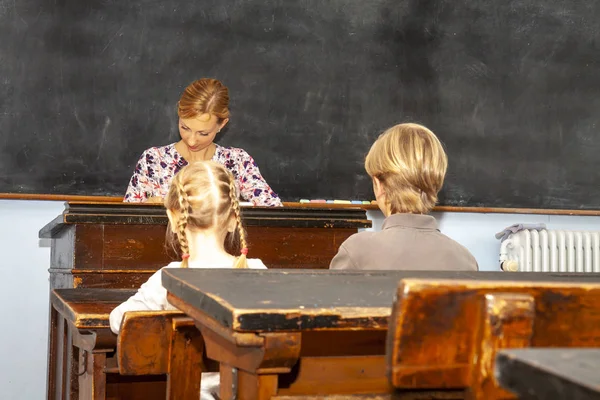 Konzept der öffentlichen Grundschulerziehung mit kleinen Jungen und Mädchen, die der Lehrerin zuhören — Stockfoto