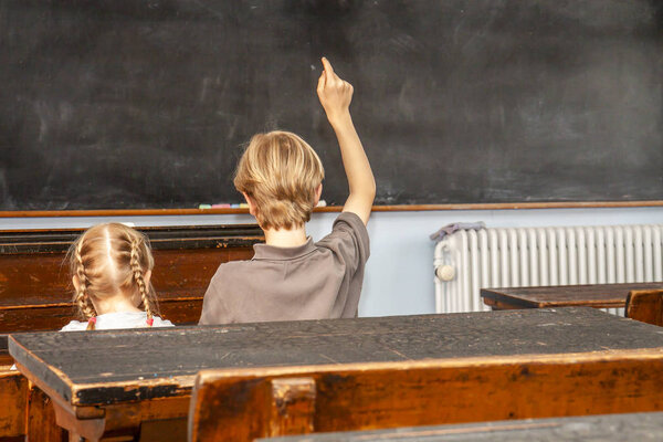 Concept of public primary school education with young boy and girl sitting in the classroom