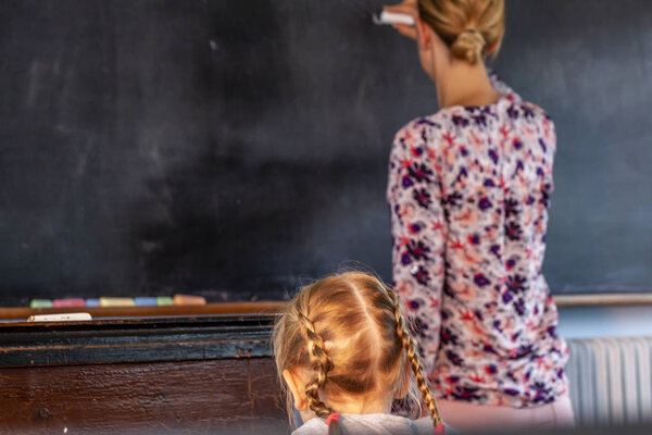Concept of public primary school education with young girl listening to the female teacher