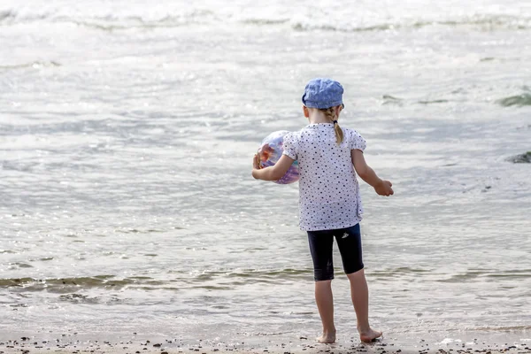 Liten flicka som leker på stranden med boll — Stockfoto