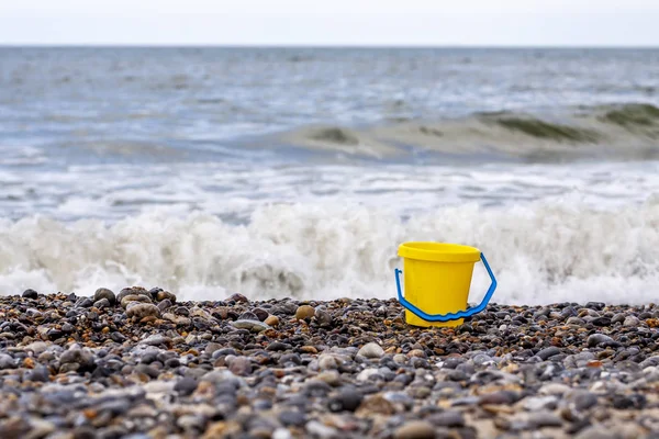 海を背景に砂利のビーチでの孤独なバケツ — ストック写真