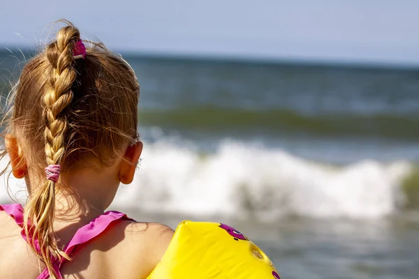 Küçük kızla mutlu floaties floaties okyanusta yüzmek için hazırlanıyor — Stok fotoğraf