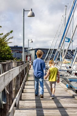 Ringkobing, Danimarka - 15 Ağustos 2018: Kardeşi ve kız kardeşi el içinde el ve liman yürüyüş