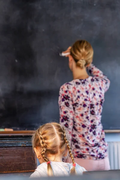 Concept of public primary school education with young girl listening to the female teacher — Stock Photo, Image