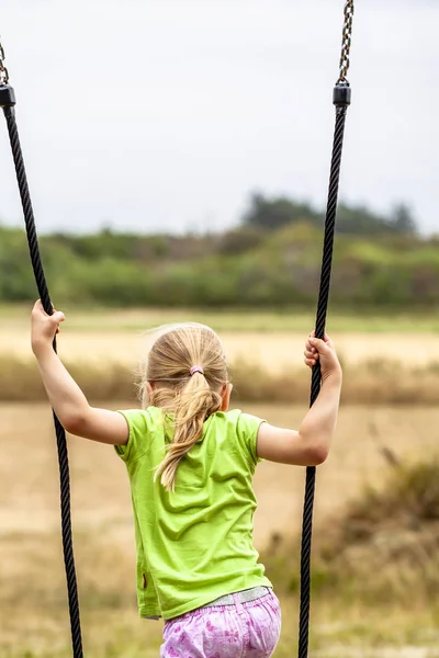 Niña divirtiéndose de pie en swing al aire libre — Foto de Stock