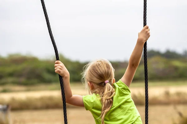 Niña divirtiéndose de pie en swing al aire libre — Foto de Stock