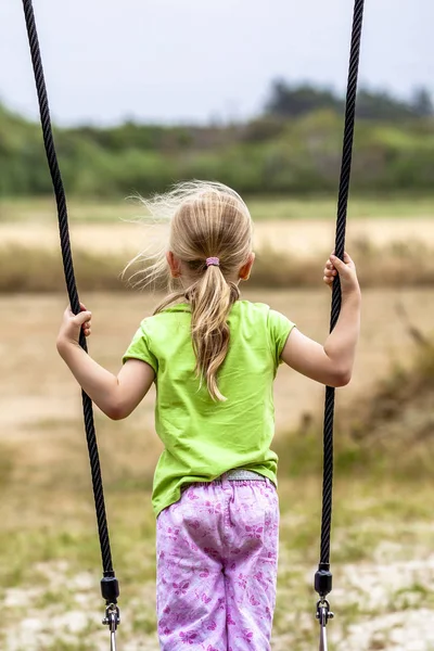 Niña divirtiéndose de pie en swing al aire libre — Foto de Stock