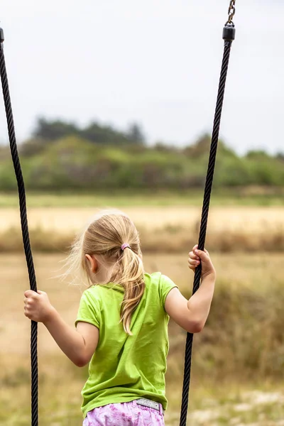 Mała dziewczynka, dobra zabawa, stojąc na zewnątrz swing — Zdjęcie stockowe