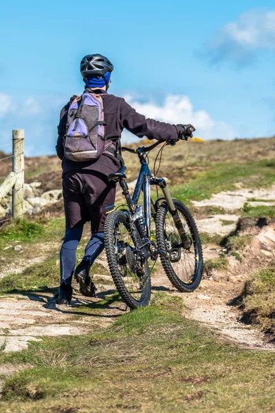 Sportsman is pushing his bike up on the mountain path — Stock Photo, Image