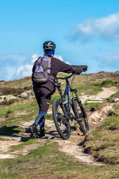 Sportsman is pushing his bike up on the mountain path — Stock Photo, Image