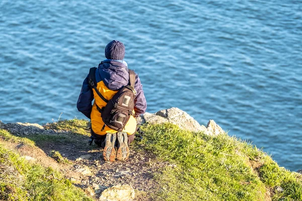 Personne agenouillée sur un sommet de montagne et regardant vers le bas les falaises — Photo