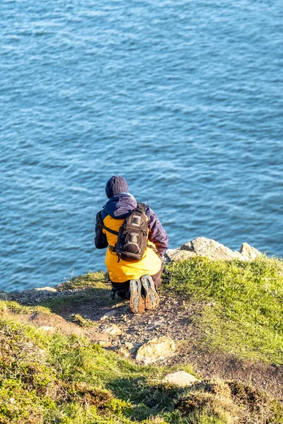 Personne agenouillée sur un sommet de montagne et regardant vers le bas les falaises — Photo