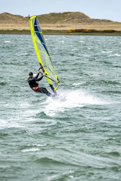 Mann windsurfen nahe der stadt caernarfon in wales - vereinigtes königreich — Stockfoto