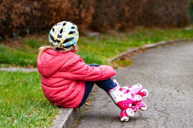 Küçük kız bir parkta paten ile eğleniyor