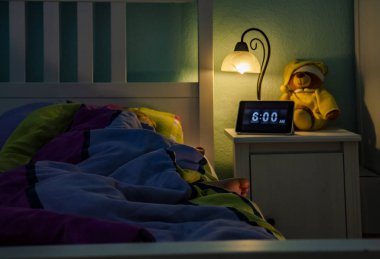 Küçük kız yatakta - çalar saat sabah 6 am uyku.