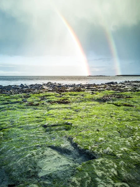 Regnbåge ovan de berömda dinosaurie fotavtryck på en Corran beach by Staffin på isle of Skye — Stockfoto