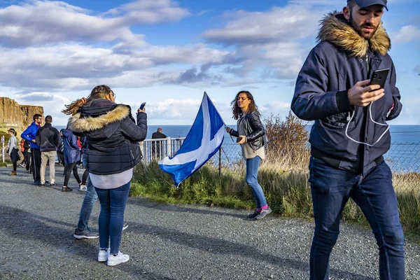 ÎLE DE SKYE, ÉCOSSE - 14 OCTOBRE 2018 : Les touristes visitent la cascade de Kilt Rock par Staffin avec un drapeau agitant — Photo
