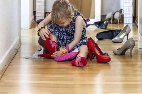 Маленькая девочка в больших туфлях матерей на высоких каблуках — стоковое фото