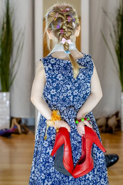 Petite fille regardant dans le miroir à la maison portant une jupe, une écharpe et des chaussures rouges de la mère — Photo