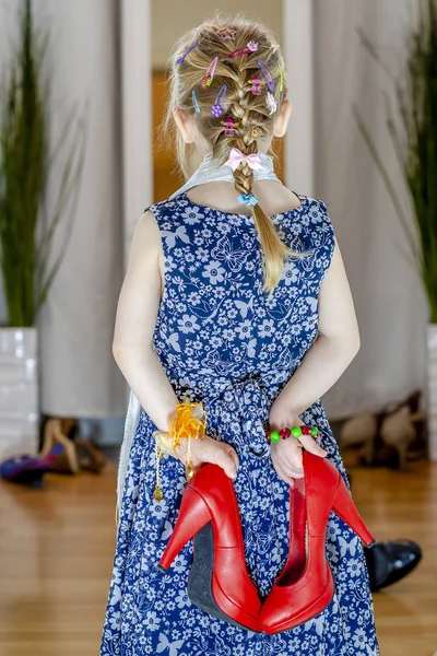 Mała dziewczynka, patrząc w lustro w domu na sobie spódnicę, szalik i czerwone buty matki — Zdjęcie stockowe